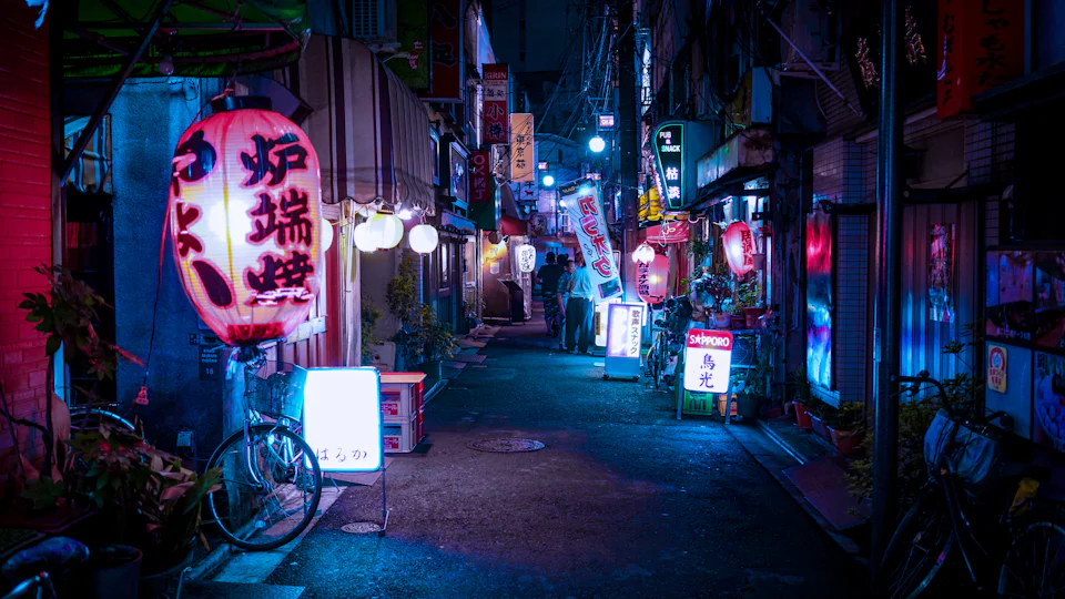 Narrow Tokyo alley at night lit by paper lanterns and neon signs